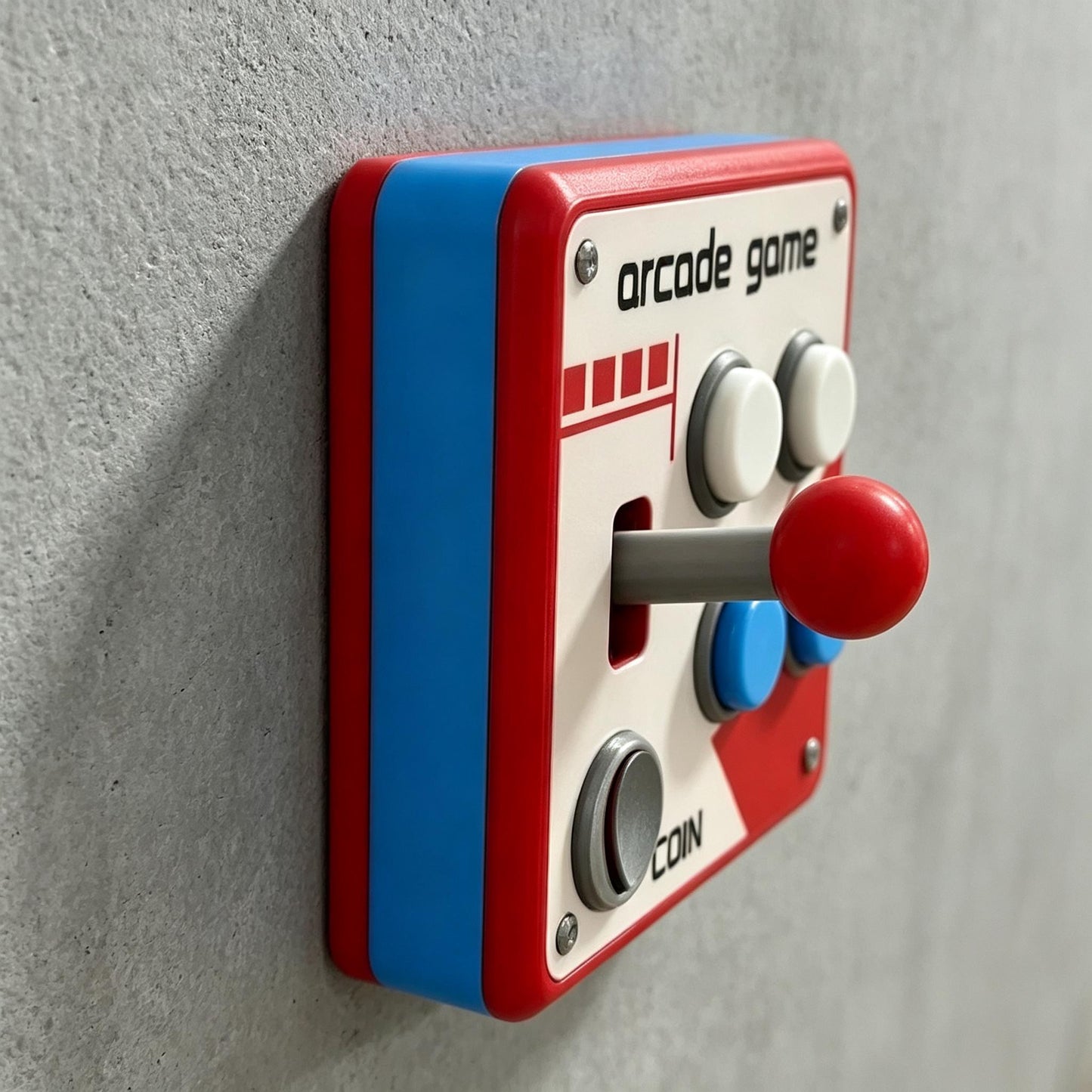 May include: A square light switch cover featuring a red and blue frame with a white faceplate. The design includes the text arcade game and coin, a red joystick, two white buttons, two blue buttons, and a gray button, all mounted on a wall.
